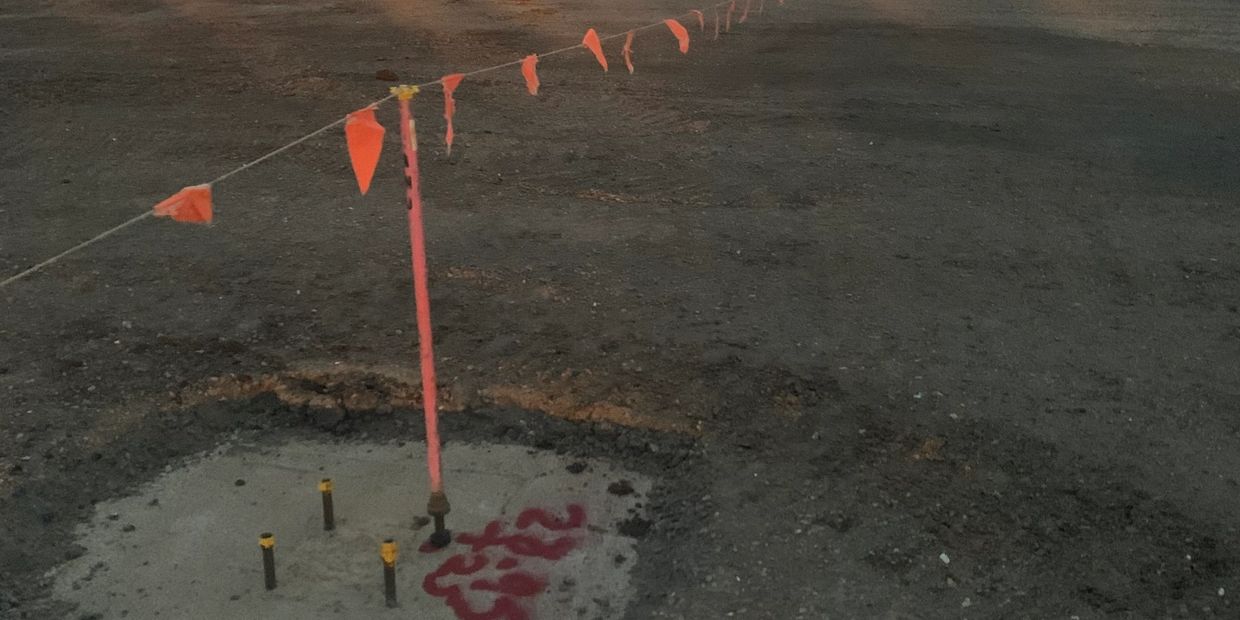Construction excavation site with safety flags and markers